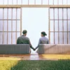 Couple sitting apart on a sofa holding hands, a common sign of an unhealthy long-term relationship.